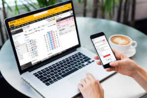 Laptop and iphone placing bet on betfair with emailed tips